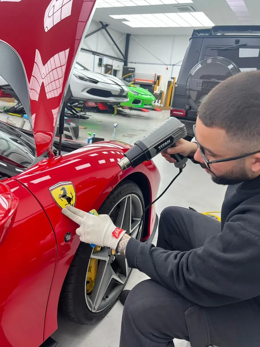 Fundador aplicando película em uma Ferrari vermelha