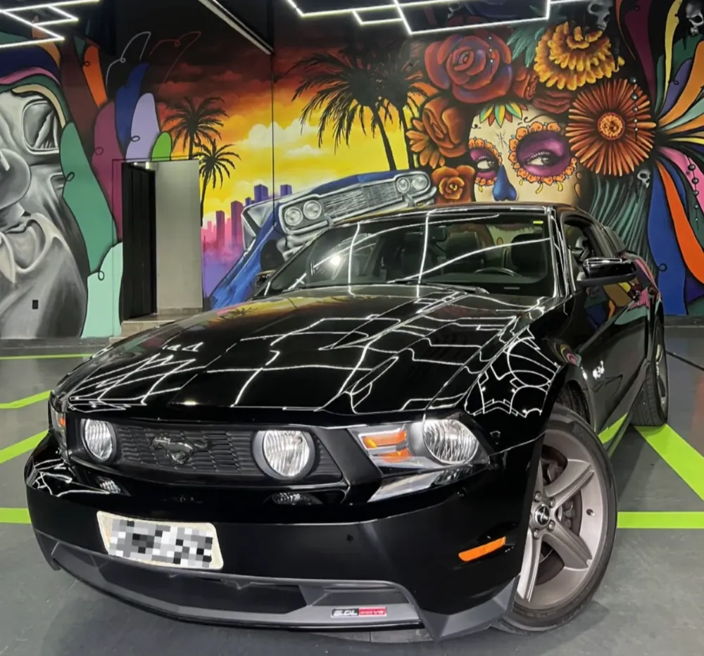 Ford Mustang preto em frente ao mural